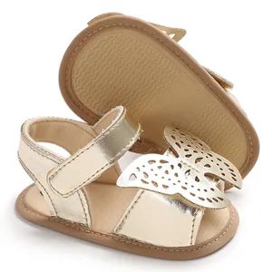 Primer plano de sandalias doradas para bebé con mariposa cortada con láser y suela antideslizante