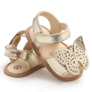 Detalle de sandalias doradas brillantes para bebé con gran diseño de mariposa y cierre de velcro seguro