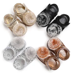 Détail de chaussures de marche pour bébé avec semelle souple, imprimé léopard et pompons.