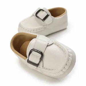 Close-up of white soft-sole baby loafers with textured leather and metal buckle.
