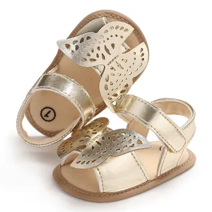 Detalle de las sandalias doradas para bebé con elegante diseño de mariposa calada