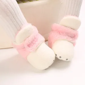 Primer plano de botas de invierno para bebé en felpa rosa con suelas antideslizantes