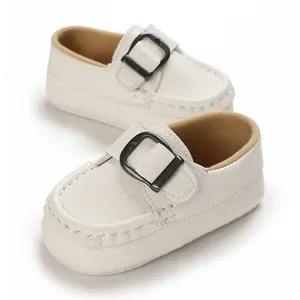Close-up of white soft-soled baby loafers with metal buckle detail