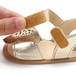 Primer plano de sandalia dorada para bebé con detalle de mariposa y velcro.