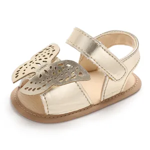 Detalle de sandalia dorada para bebé con mariposa calada y suela suave de silicona