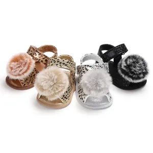 Close-up view of cute baby leopard print sandals with soft fluffy pom-pom details