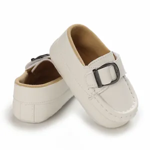 Close-up detail of soft white leather baby loafers featuring a stylish black buckle