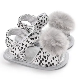 Detailed view of baby leopard print sandals featuring soft grey pom-poms and velcro straps