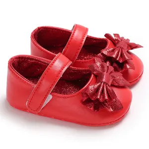 Vue détaillée de chaussures de marche rouges pour bébé fille avec un nœud pailleté brillant