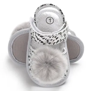 Detailed macro view of silver baby leopard sandals featuring a soft grey fur pom-pom.