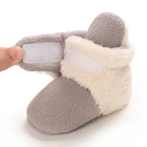 Detalle del cierre de velcro y el forro de felpa suave de una bota de nieve gris para bebé.