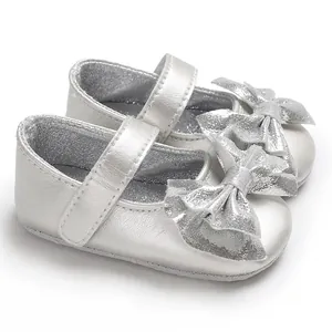 Vue détaillée de chaussures Mary Jane argentées pour bébé avec nœud pailleté et scratch.