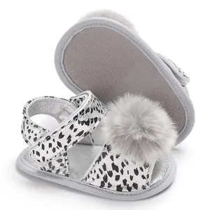 Detail view of silver leopard baby sandals with grey fluffy pom-poms