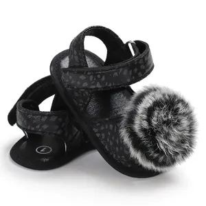 Vue détaillée de sandales pour bébés filles avec un pompon moelleux noir et blanc
