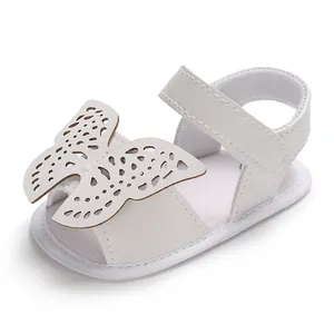 Detalle de sandalias blancas para bebé con un diseño decorativo de mariposa calada.