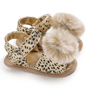 Close-up detail of infant leopard print sandals featuring soft beige fluffy pom-poms