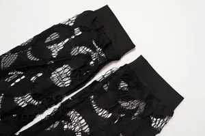 Primer plano de tela de encaje negro con detalles desgastados y puños elásticos negros