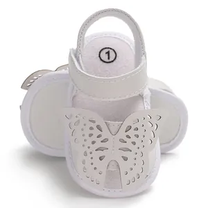 Primer plano de sandalias blancas para bebé con detalle de mariposa láser