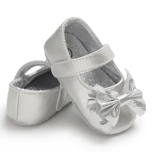 Gros plan d'élégantes chaussures Mary Jane argentées pour bébé avec un nœud pailleté