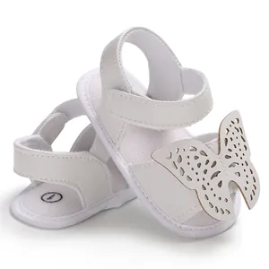Primer plano de sandalias blancas para bebés con mariposa y suela suave antideslizante