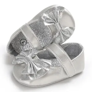 Vue détaillée de chaussures pour bébé en argent pailleté avec de grands nœuds décoratifs
