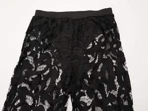Detalle de los pantalones anchos de encaje negro con intrincados motivos florales