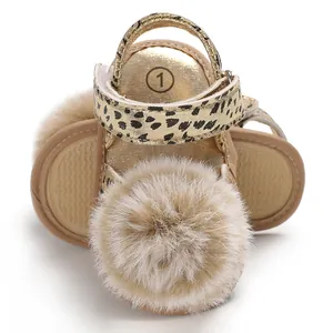Close-up of baby leopard print sandals with large fluffy beige fur pom-pom detail