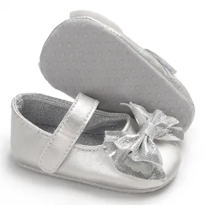 Détail de chaussures de princesse argentées avec nœud et structure de semelle antidérapante.