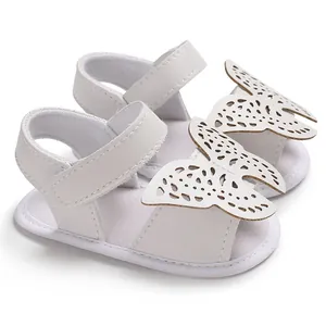 Primer plano de sandalias blancas para bebé con elegantes mariposas cortadas con láser