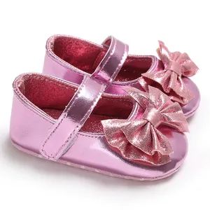 Détail de la finition rose métallisé et du grand nœud sur ces chaussures de princesse bébé