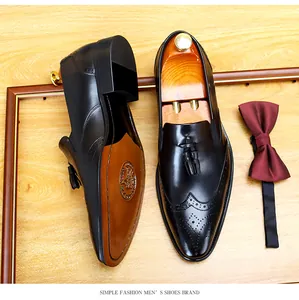 Hochwertige Detailansicht schwarzer Herren-Brogue-Lederschuhe mit Quasten auf Holz