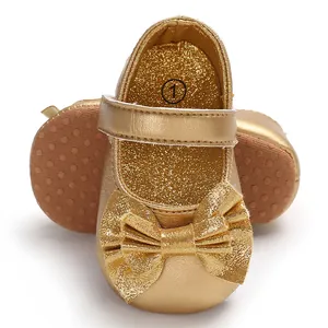 Gros plan d'élégantes chaussures dorées pour bébé avec un grand nœud et semelle scintillante