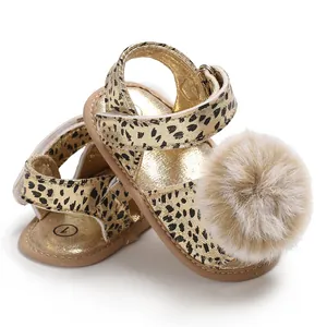 Close-up detail of infant leopard print sandals featuring a fluffy pom-pom and soft sole