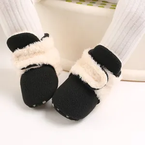 Primer plano de botas de nieve para bebé forradas de vellón con textura de felpa crema.
