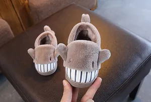 Close-up of cute shark-themed plush children's winter slippers with warm fur lining