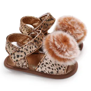 Close-up detail of baby leopard print sandals featuring soft brown pom-poms and velcro straps