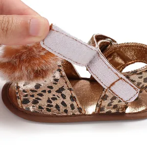 Close-up showing the adjustable velcro strap detail on leopard print baby pom-pom sandals