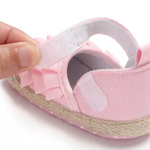 Detailed macro view showing the velcro closure on a pink ruffled baby girl walking shoe