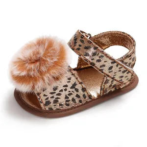 Detailed view of baby leopard print sandal with fluffy brown pom-pom and gold finish.