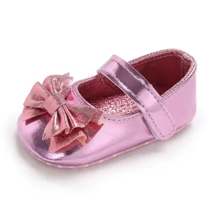 Gros plan de chaussures de princesse rose métallisé pour bébé avec un grand nœud