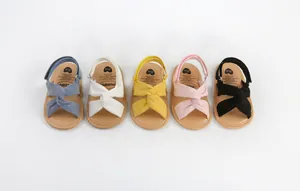 Sandalias suaves para bebé con correas cruzadas de tela en cinco colores brillantes.