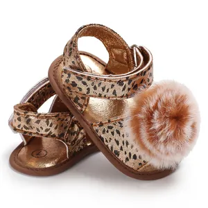 Detailed shot of infant leopard print sandals featuring a large fluffy pom-pom decoration
