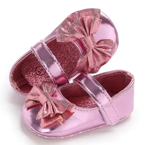 Vue détaillée de chaussures de bébé roses métallisées avec nœud scintillant et bride.