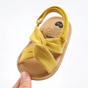 Primer plano de sandalias amarillas para bebé con tiras cruzadas y cierre de velcro