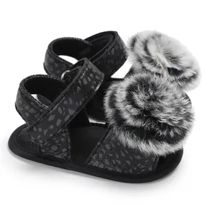 Detail view of baby leopard print sandals featuring soft black faux fur pom-poms.