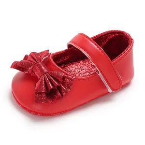 Gros plan sur des chaussures rouges de princesse pour bébé avec nœud brillant.