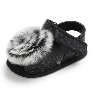 Close-up of black baby leopard print sandal featuring a soft faux fur pom-pom detail