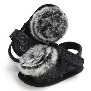 Detailed view of baby leopard print sandals featuring large grey and white fur pom-poms.