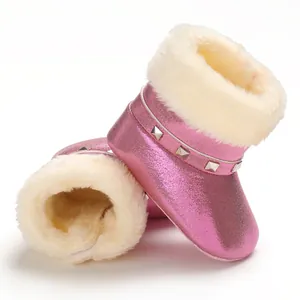 Détail de bottes de neige roses pour bébé avec doublure en peluche et clous.