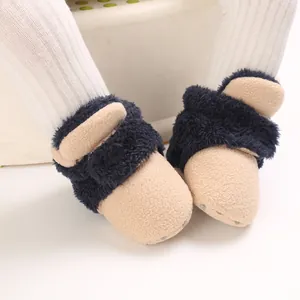 Primer plano de botas de nieve de peluche para bebé con forro suave y suela antideslizante.